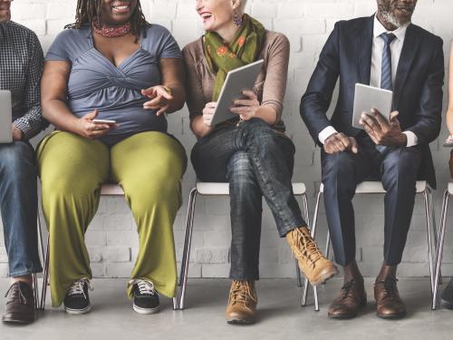 Stock photo of a diverse group of people sharing information on their devices.