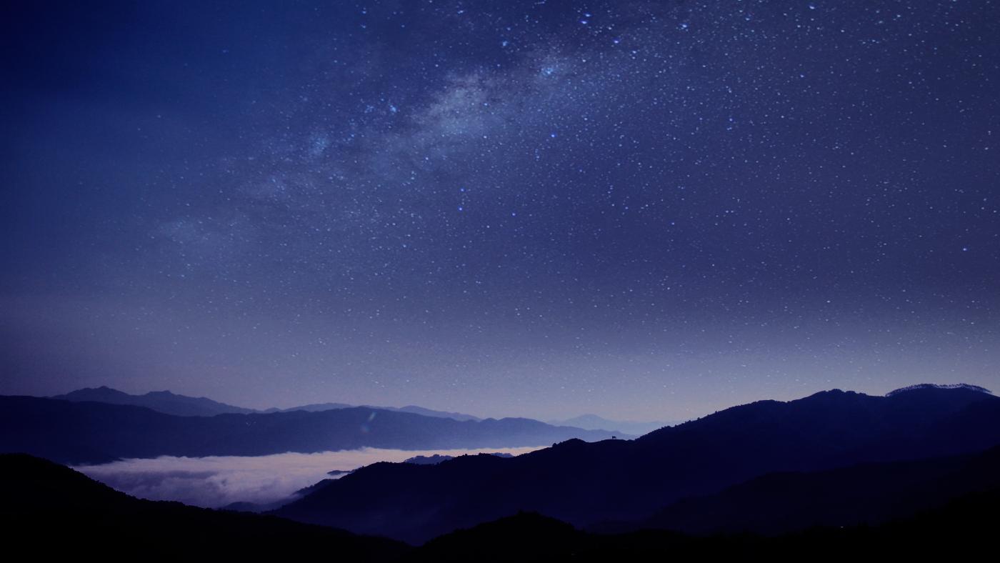 Silhouette of mountains against blue night sky with stars