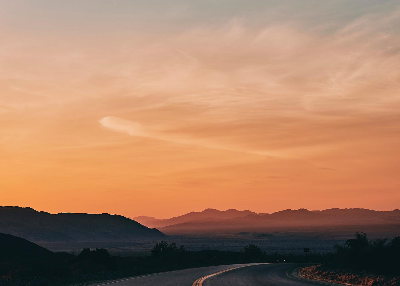 View down empty California road across the desert at sunset